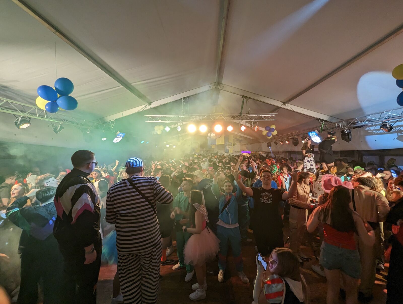 Crowd under white spotlight beams at a tent party