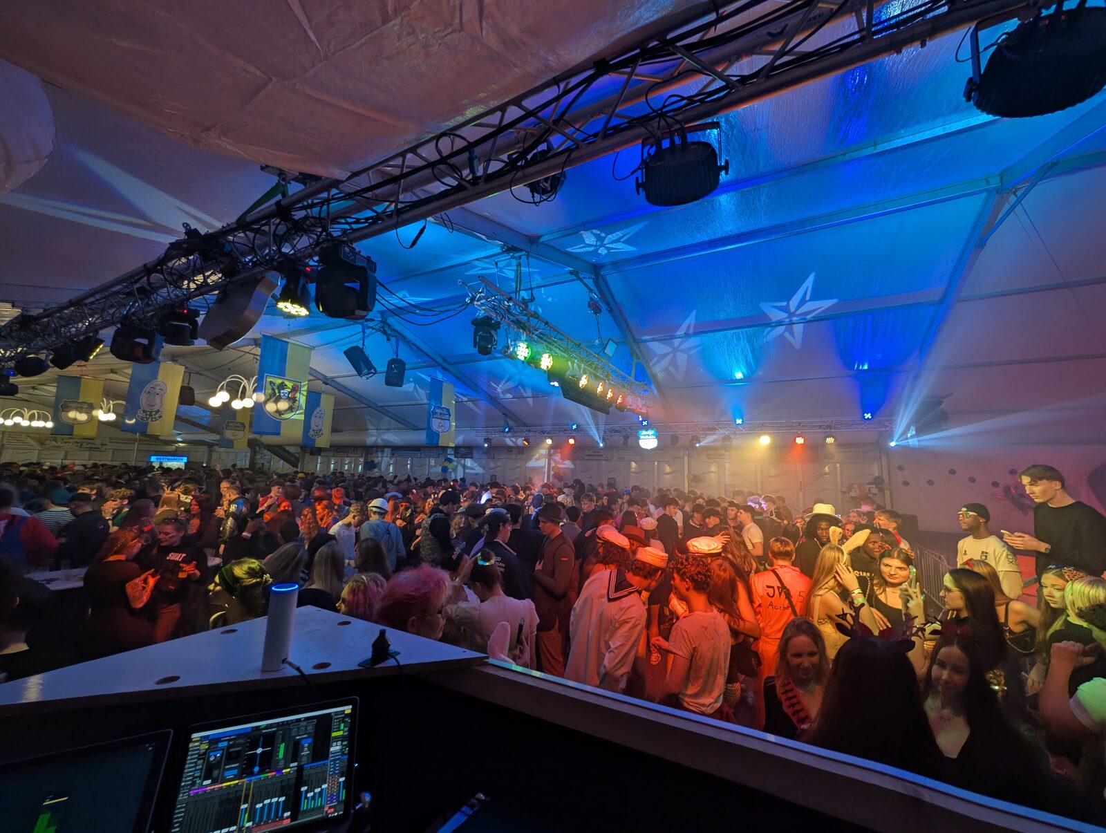 View from the FOH over a packed festival tent with truss and moving heads