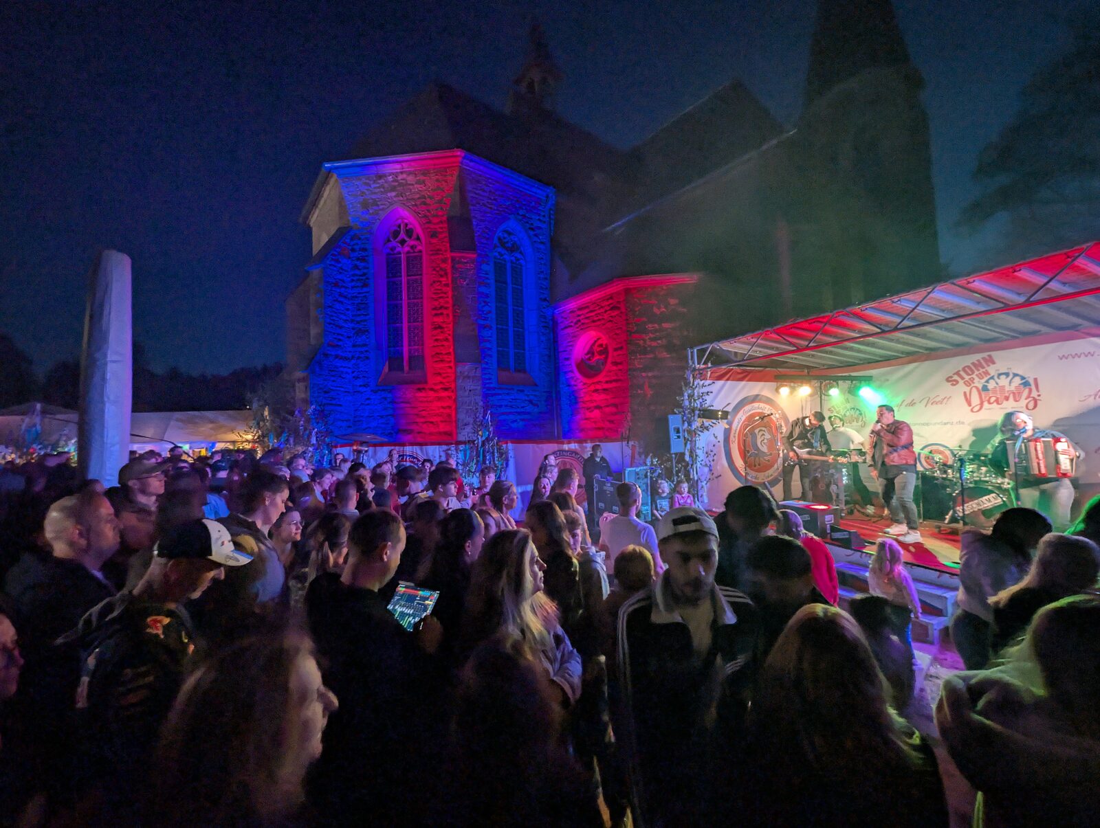 Night open-air with stage production and red-blue uplighting on a church